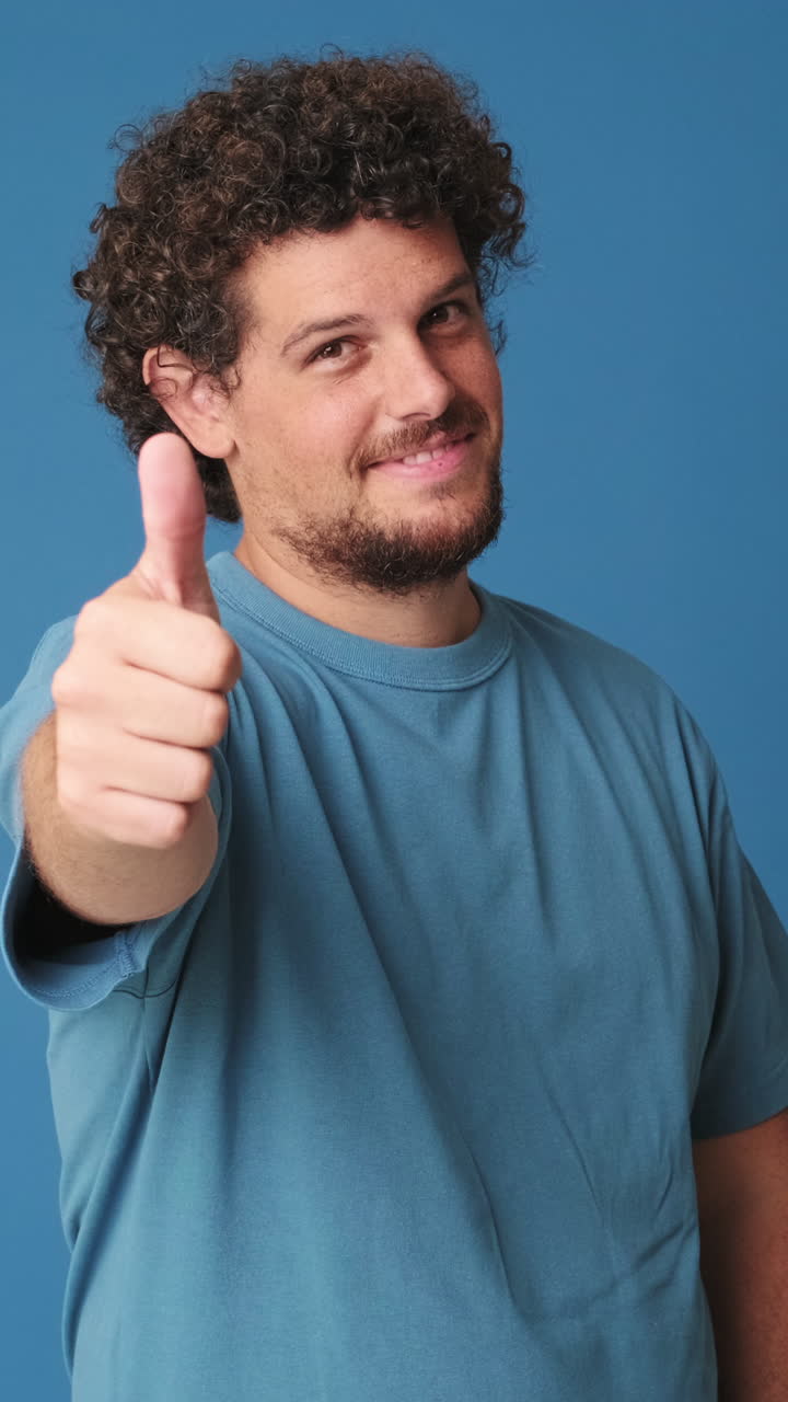 Hombre sonriente con el pulgar hacia arriba sobre fondo azul