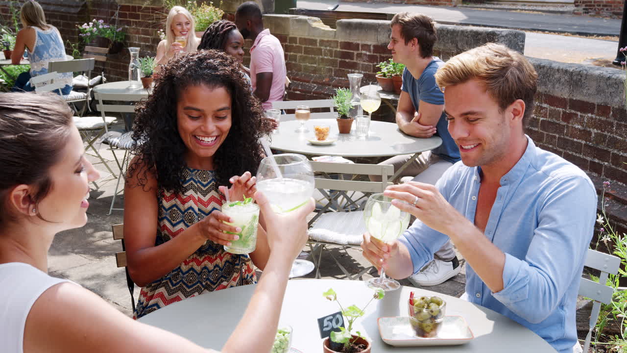 Group Of Friends Meeting For Drinks At Outdoor Tables In Restaurant