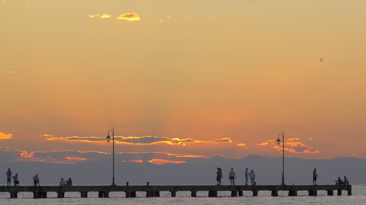 Cinemagraph - People enjoying seascape from the pier at sunset
