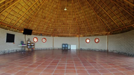 spacious round building with thatched roof and terracotta floor