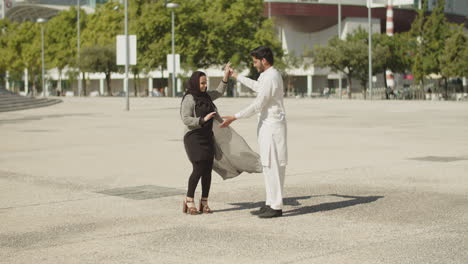 young muslim couple performing traditional dance outside.