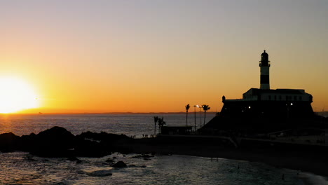 Aerial-view-of-Farol-da-Barra-and-the-ocean,-at-sunset,-Salvador,-Bahia,-Brazil