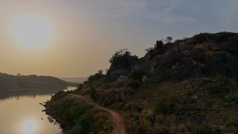 Aerial---Descending-wide-shot-of-a-man-walking-on-a-dirt-road-at-sunset