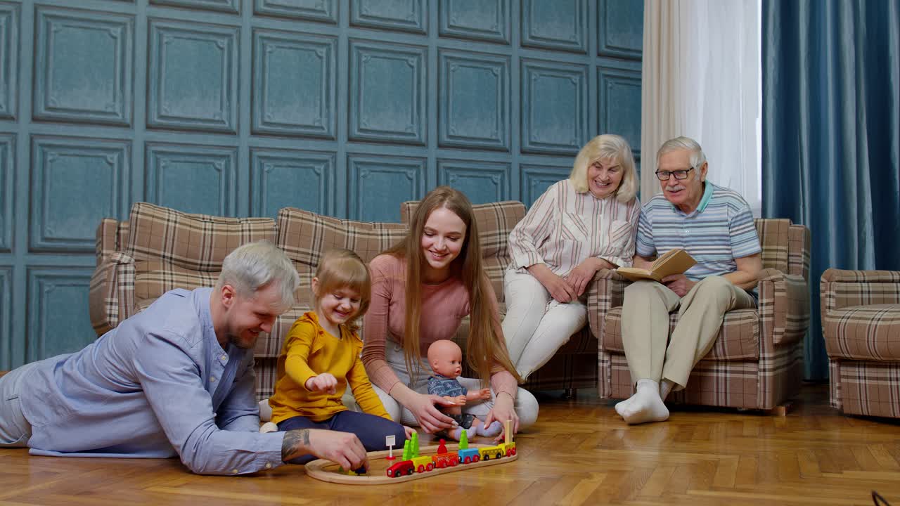 Familiehygge derhjemme, barn datter leger med mor og far med legetøjstogbane.