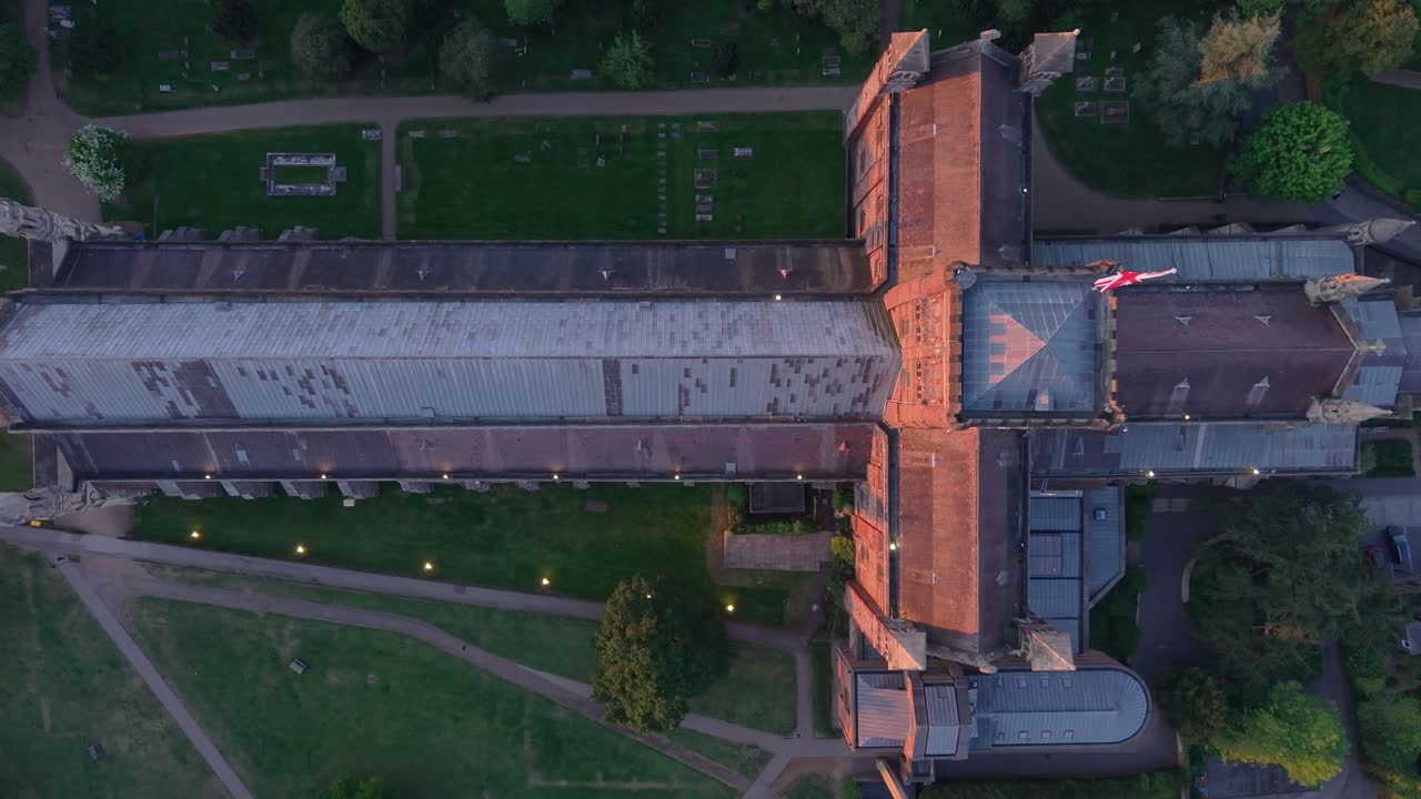 A cinematic top-down aerial view captures the full structure of St Albans Cathedral, showcasing its gothic design, historic architecture, and surrounding landscape