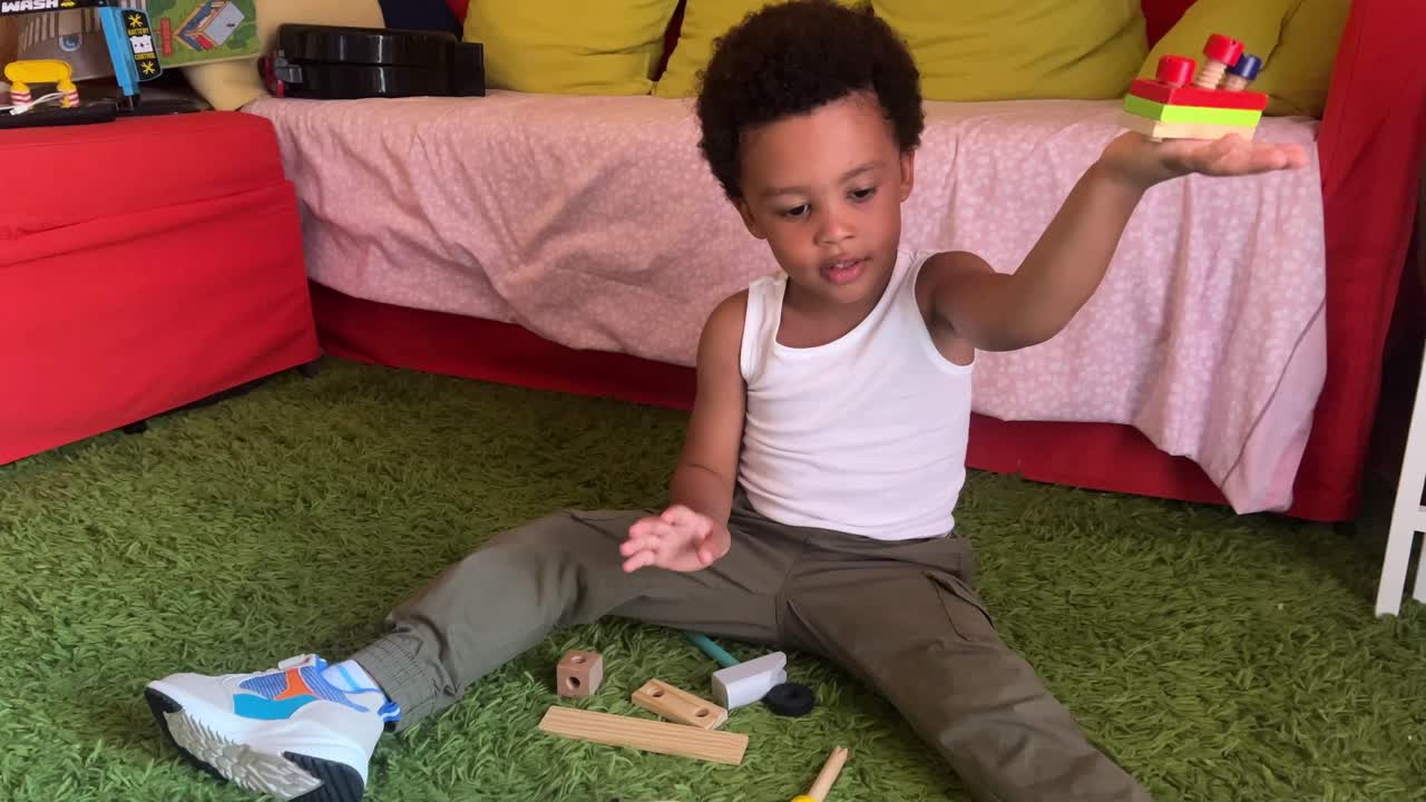 Playful 3-year-old expressive and cute black child playing at home with block construction set and tools