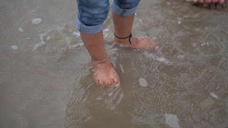 cute close up shot legs of the baby that makes first steps on the sand beach