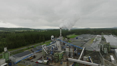 lumber mill with piles of saw dust emitting gases from smokestack, aerial