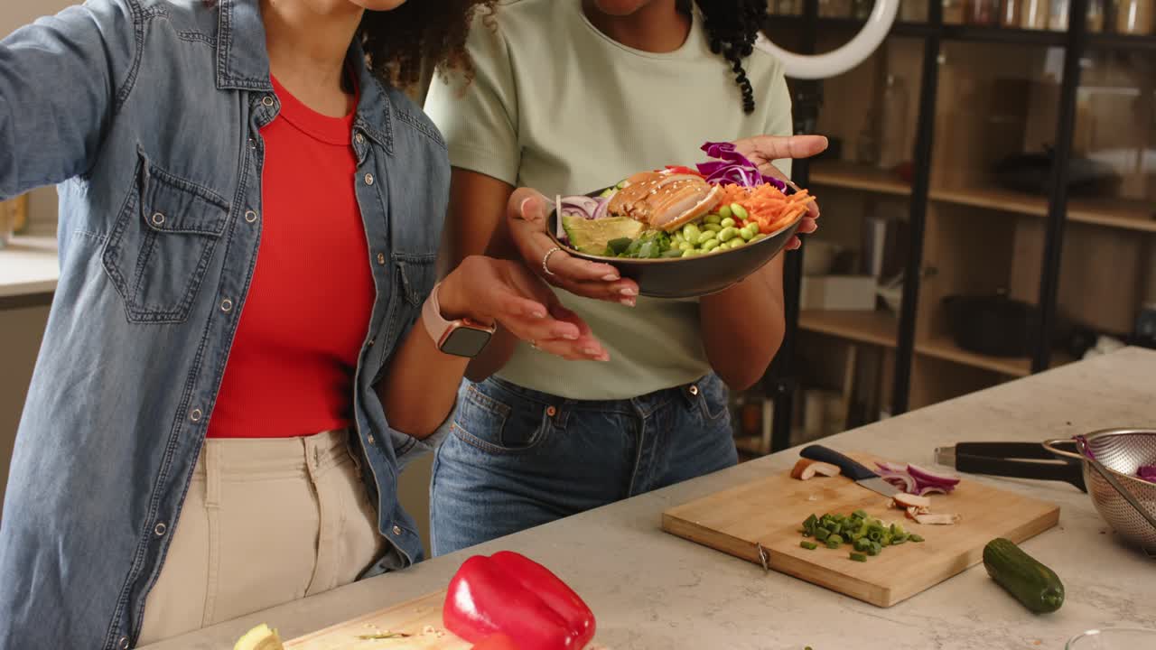 Diverse presentatrici che salutano con la mano e inclinano l'insalata di salmone sotto la ring light, evidenziando le verdure a strati