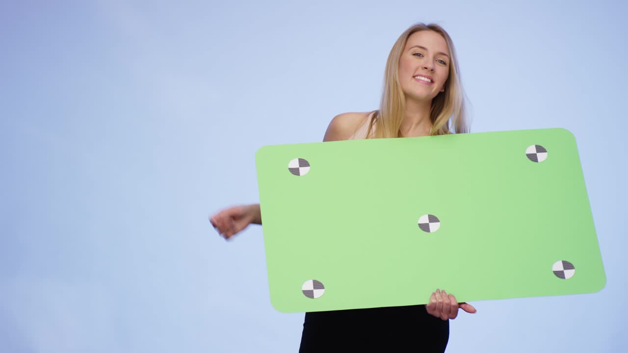 Very attractive Woman holding oversized blank Card and pointing on it