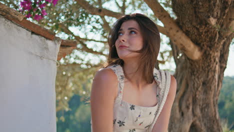 portrait girl enjoy wind touching hair under tree. smiling woman looking camera