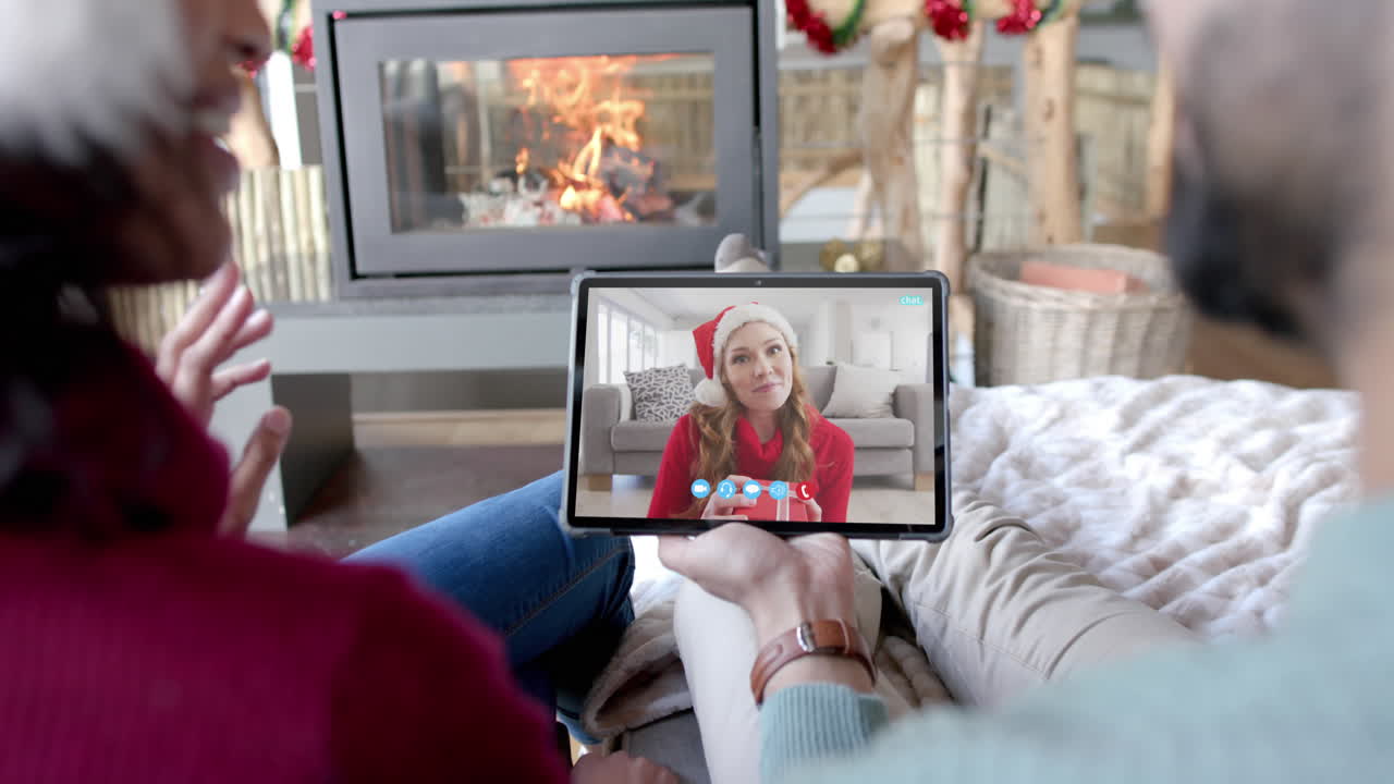 Coppia felice di diverse etnie e un'amica che fanno una videochiamata di Natale via tablet, al rallentatore