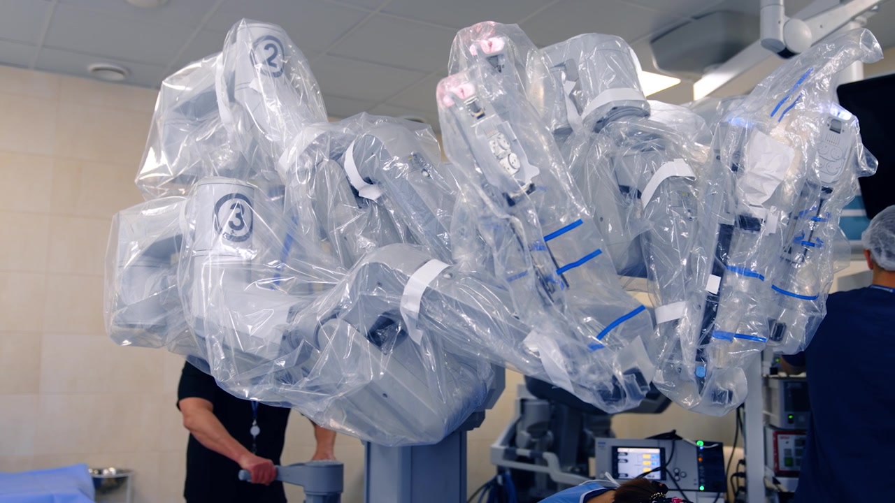 Robot Da Vinci coperto con plastica per garantire la sterilità durante l'intervento. Il medico sposta l'attrezzatura più vicino al tavolo operatorio.