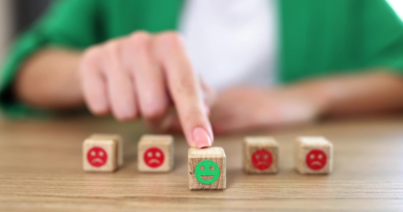 Kadın, kaşlarını çatmış yüzler arasındaki gülen yüz emojili küpü işaret ediyor.