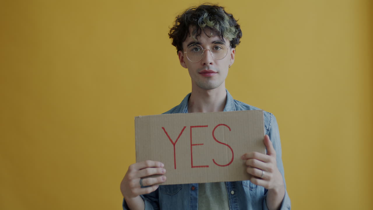 Man holding a cardboard sign that says 'YES'