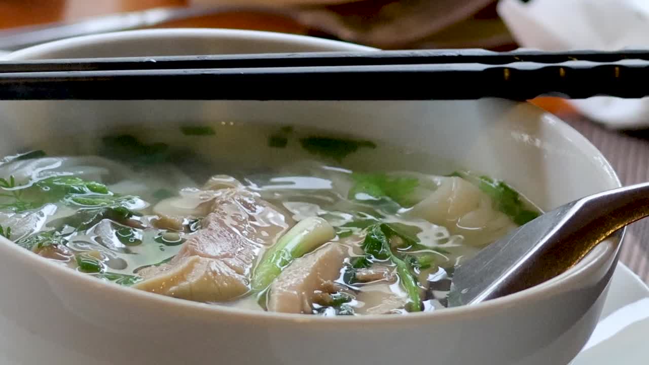 A close-up of lime juice and chili slices enhancing a steaming bowl of pho.