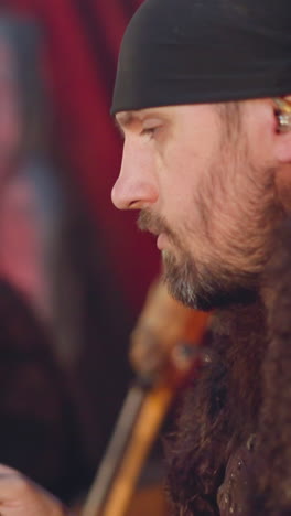 performer taps drums with fur sticks playing ethnic music with friend in ail premise closeup slow motion. drummer performs with old instruments