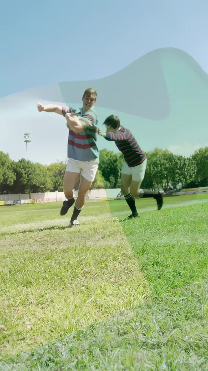 Vertikální video: Hráč běží po ragbyovém hřišti, pronásledovatel dosahuje a vykopává volný míč, aby vyhrál.
