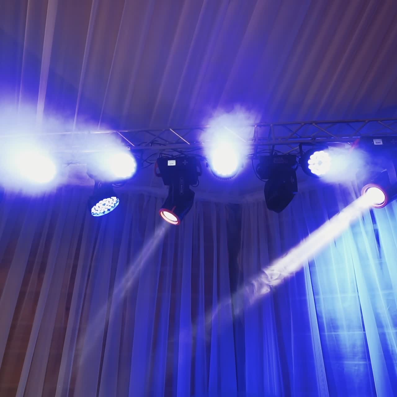 Animation of stage lights frame. Bright shiny lights flashing with blue from spotlight projectors in the dark. Led lighting equipment.
