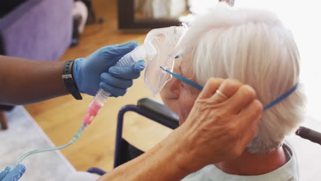 video of hands of african american male doctor keeping oxygen to caucasian senior woman