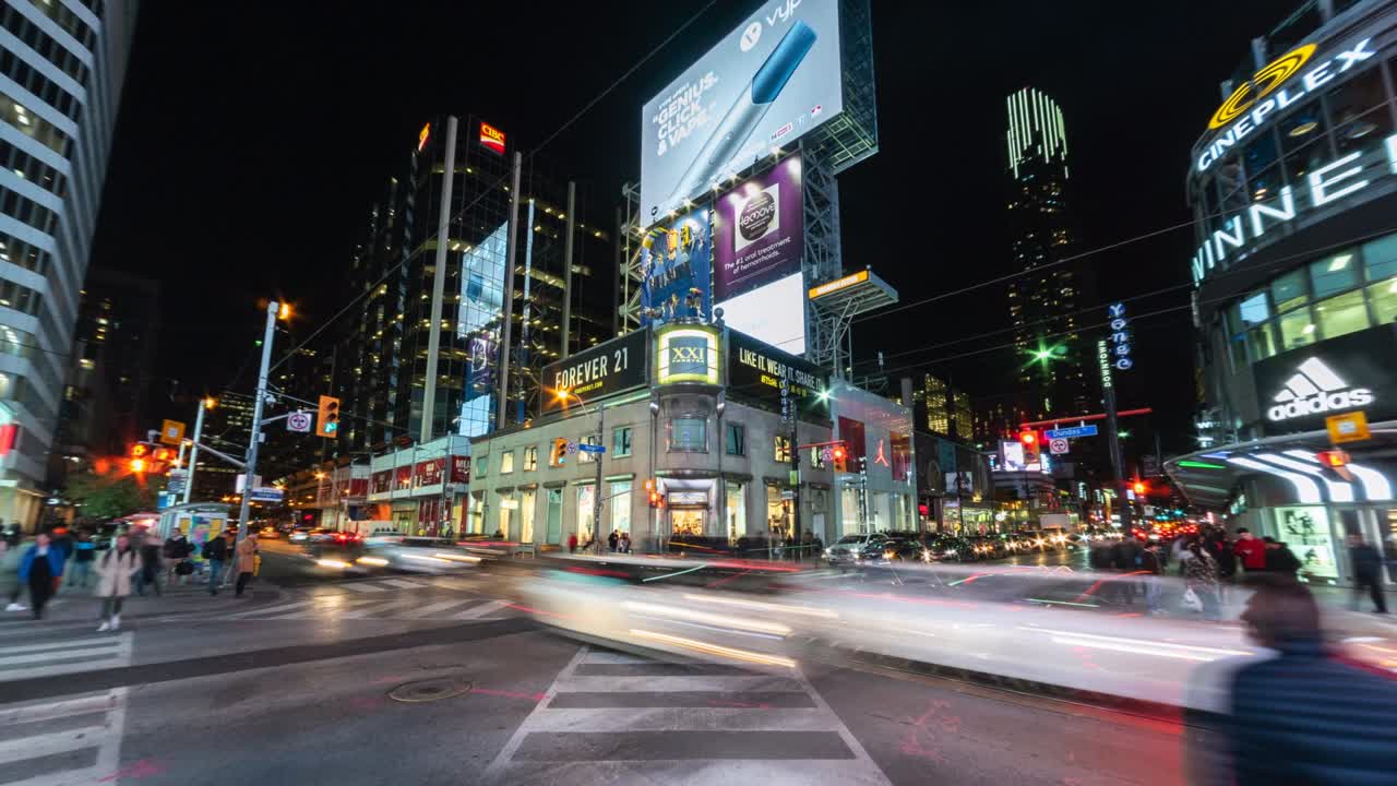 Night time lapse view of people and traffic at busy Yonge-Dundas intersection in downtown Toronto, Ontario, Canada
