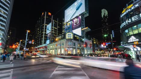 night time lapse view of people and traffic at busy yonge-dundas intersection in downtown toronto, ontario, canada