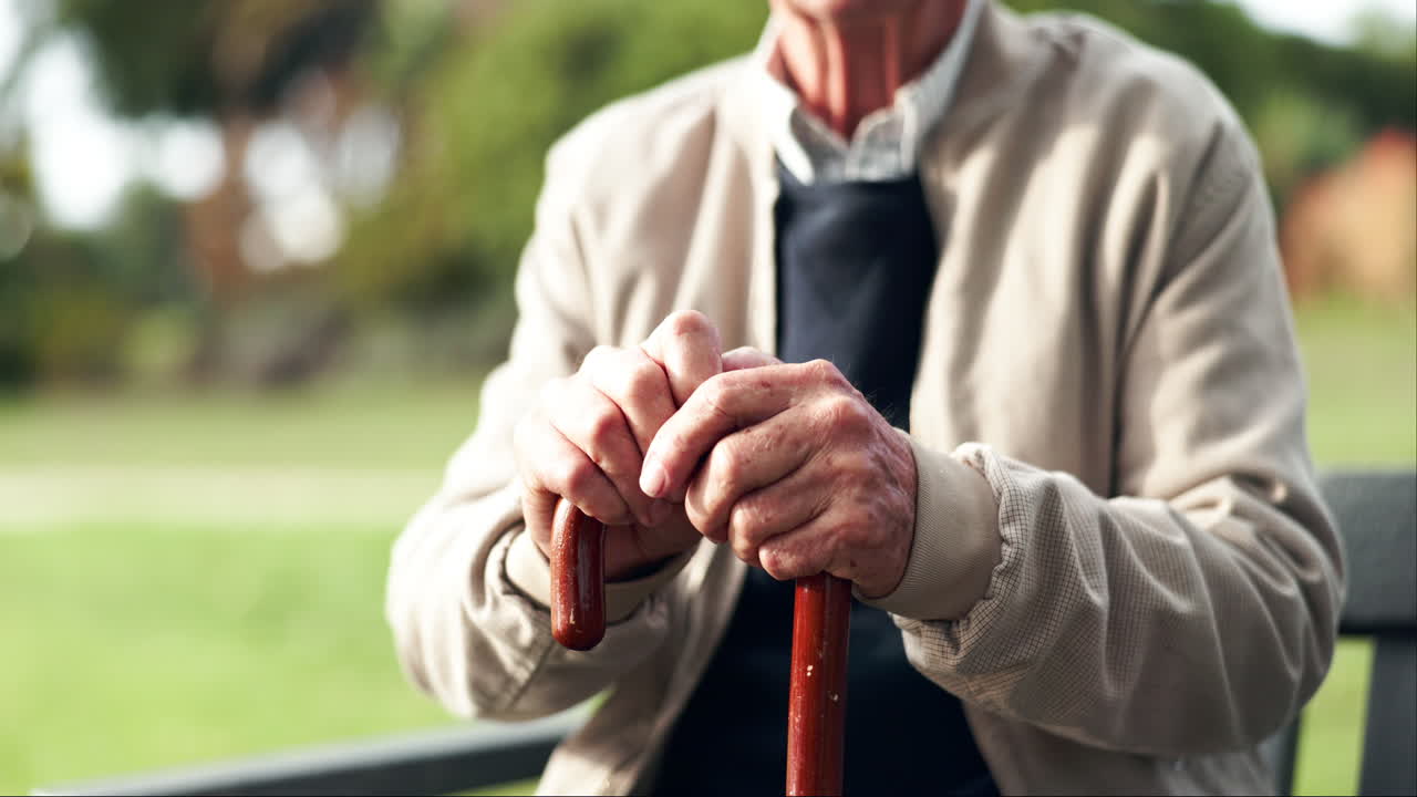 Senior Man Resting with Walking Stick in Park
