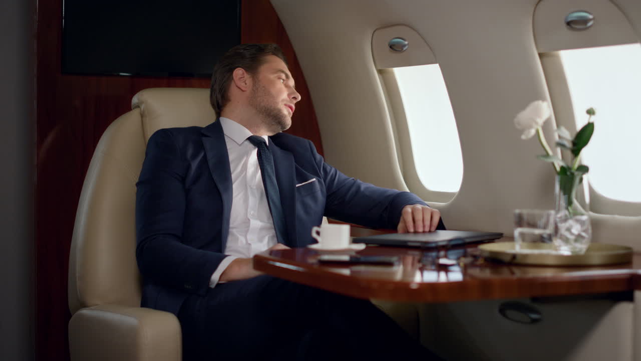 Uomo d'affari europeo che finisce il lavoro chiudendo il portatile. Uomo stanco appoggiato al sedile dell'aereo