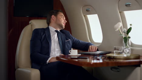 european businessman finishing work closing laptop. tired man lean airplane seat