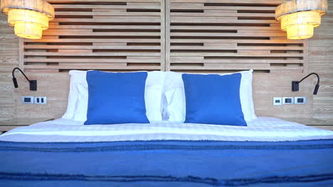 pan right to felt across a hotel suite bed made up with blue accent pillows and coverlet