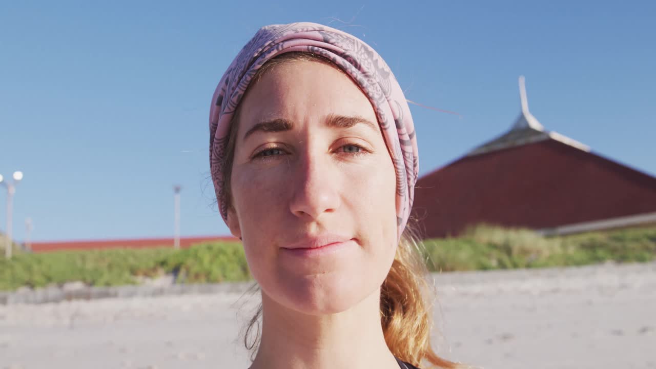 카메라를 보고 해변과 파란 하늘 배경에 미소 짓는 백인 여성