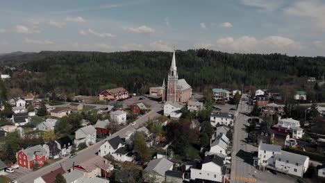 Volando-Sobre-El-Pueblo-De-Le-Bic-Con-La-Iglesia-De-Sainte-cecile-Du-Bic-En-El-Fondo-En-Bas-Saint-Laurent-En-Rimouski,-Quebec,-Canadá