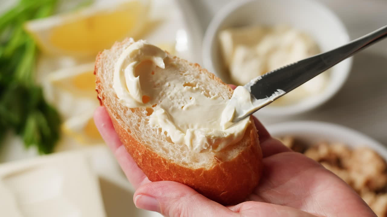 Young woman spreading nut butter onto toast in kitchen, closeup. High quality 4k footage