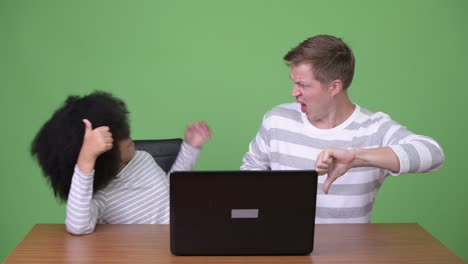 young african girl and young scandinavian man using laptop together