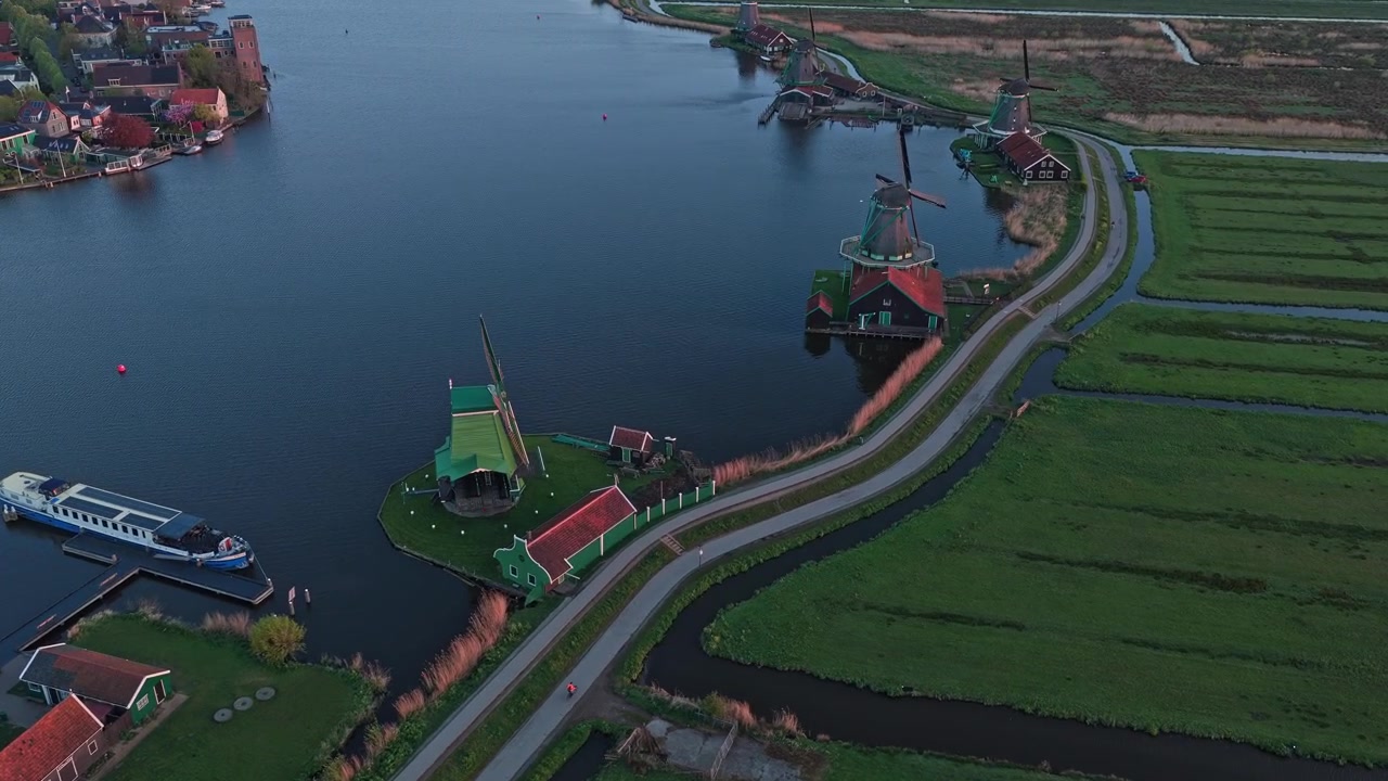 Vista aerea che sorvola gli iconici mulini a vento di Zaanse Schans. Il pittoresco paesaggio olandese presenta architettura classica e acque tranquille del fiume.