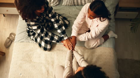 girls in pajamas put their hands together on a bed