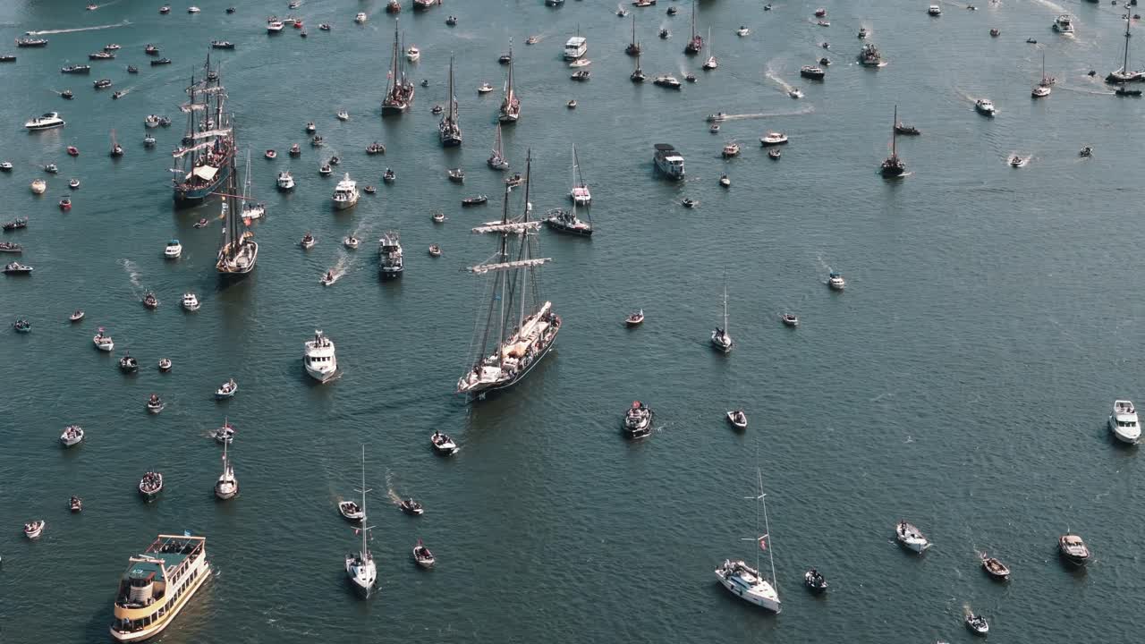 Aerial view looking down on countless boats slowly sailing out to sea