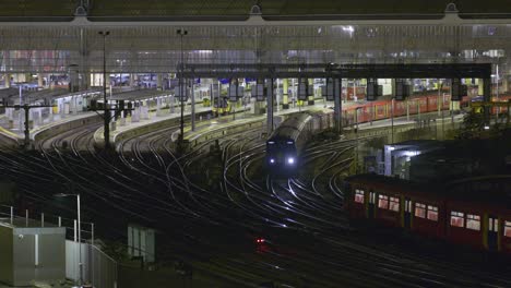 multiple trains arriving and departing at the same time at london waterloo station at night