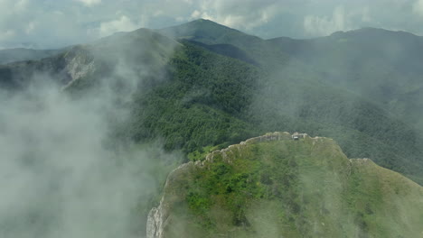 flying trough white fluffy clouds above green mountain peaks