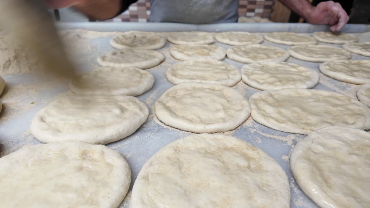 Baker Brushing Raw Dough Circles for Baking
