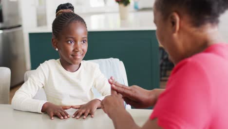 Video-of-smiling-african-american-granddaughter-practicing-sign-language-with-her-grandmother