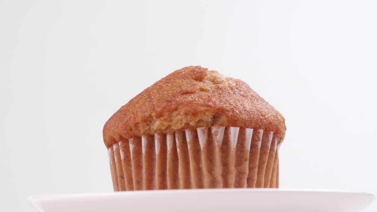 Muffin alla banana con sfondo bianco, messa a fuoco selettiva e rotazione lenta