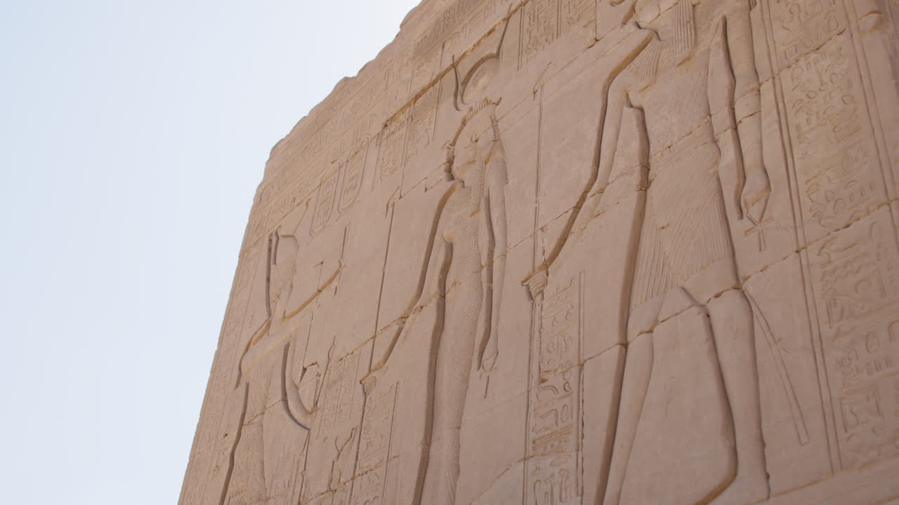 Ancient Egyptian carvings on a stone wall at Dendera, showcasing detailed hieroglyphs