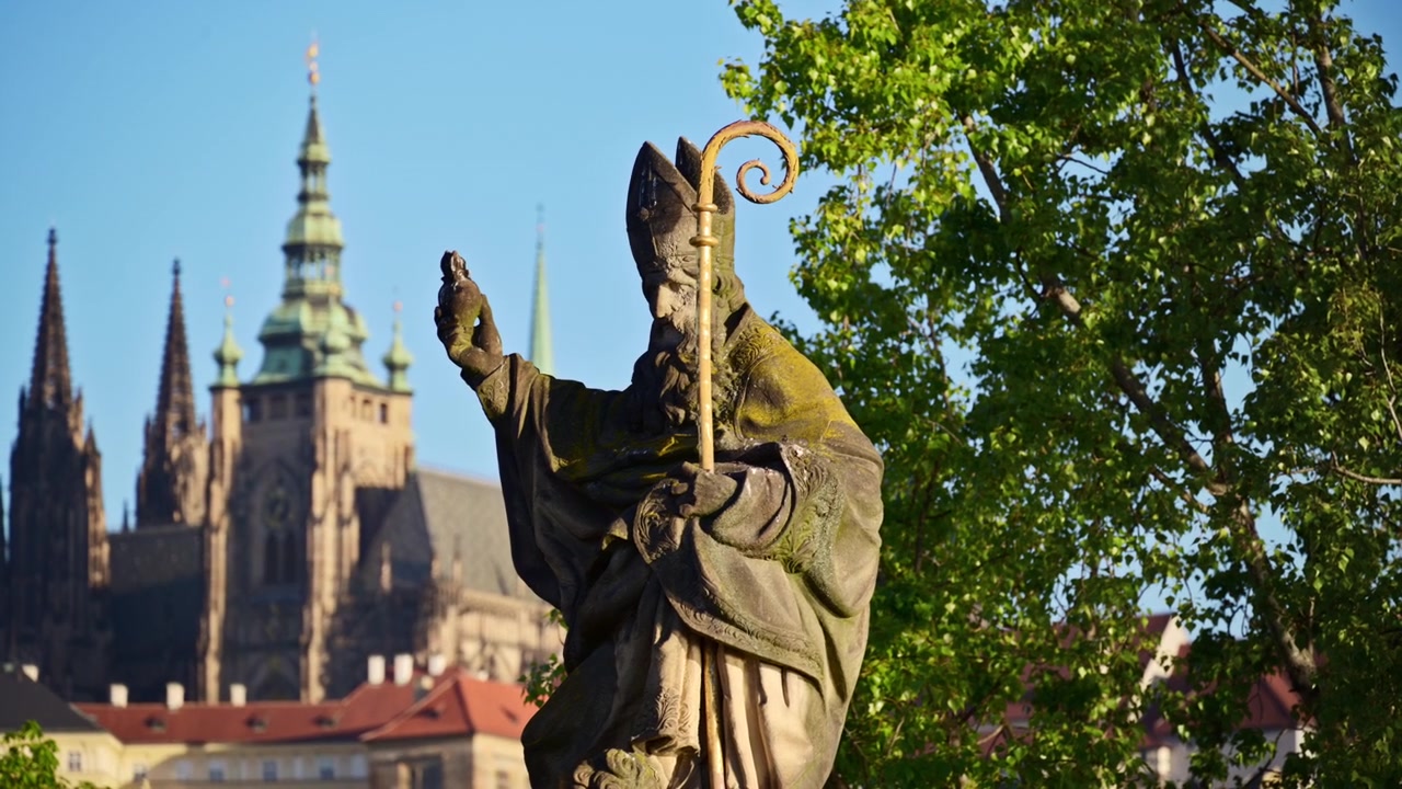 Primo piano di una statua in pietra di un vescovo con un pastorale dorato, con la Cattedrale di San Vito sullo sfondo, Praga, Repubblica Ceca