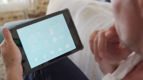 happy caucasian man sitting on sofa in living room, using tablet