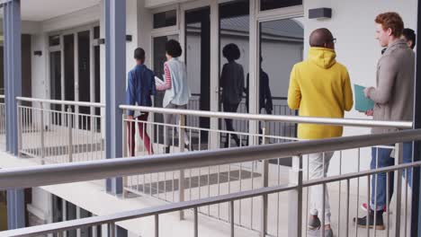 Back-view-of-diverse-group-of-male-and-female-business-colleagues-walking-through-corridor