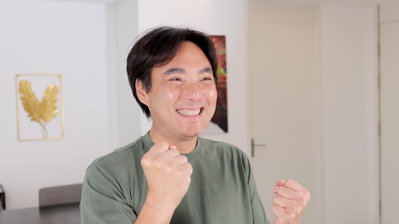 A man expresses excitement and happiness in a well-lit room, showcasing a positive and uplifting moment