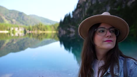 Porträt-Einer-Jungen-Frau-Mit-Hut,-Die-Sich-Einen-Moment-Zeit-Nimmt,-Um-Die-Friedliche-Landschaft-Des-Pragser-Wildsees-Zu-Genießen