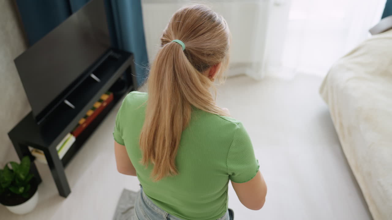 Aerial view of young woman mopping living room floor near window showing effort in maintaining clean bright home interior with care, attention, hygiene and responsibility in daily household chores