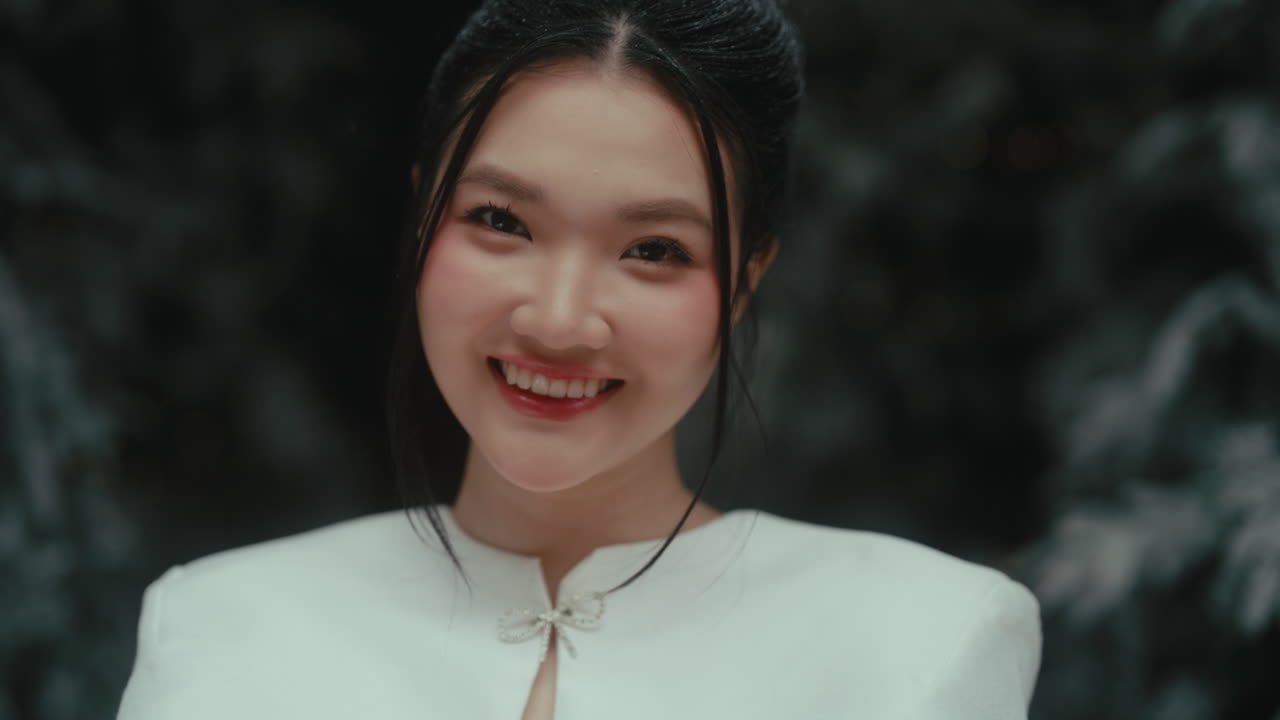 A young woman smiling warmly while preparing to blow out a candle in a snowy setting